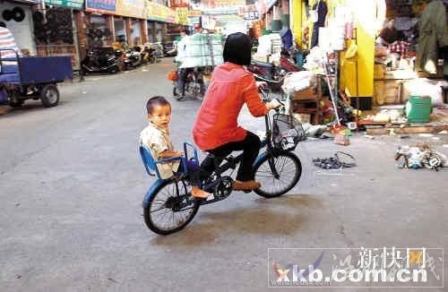 佛山五金市场，一位母亲带着孩子骑车路过事发地点。