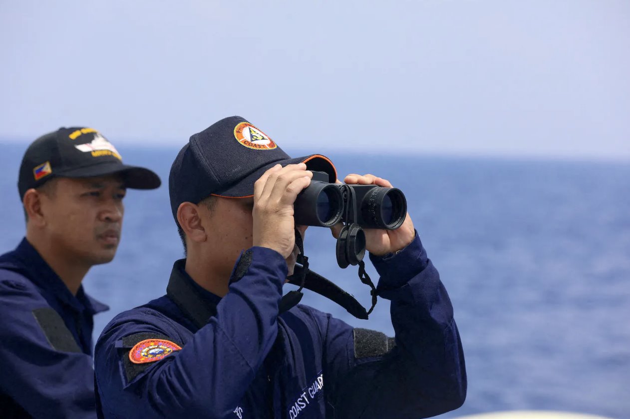 2023年10月4日，一名菲律宾海岸警卫队人员在为驻扎在南海搁浅军舰上的菲律宾军队执行补给任务时通过双筒望远镜观察。