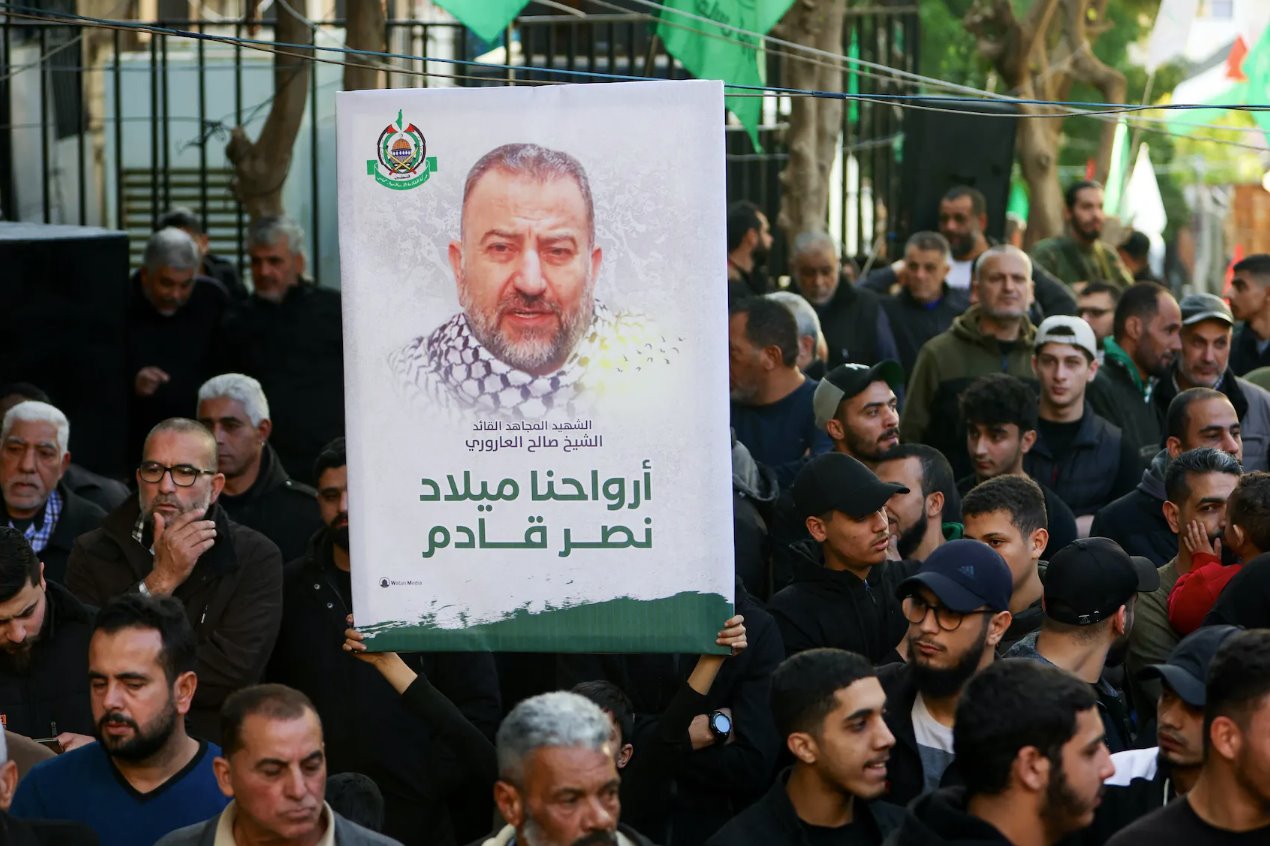 在艾哈迈德·哈穆德的葬礼上，一个人举着一张标语牌，上面挂着已故哈马斯副领导人萨利赫·阿鲁里的照片。