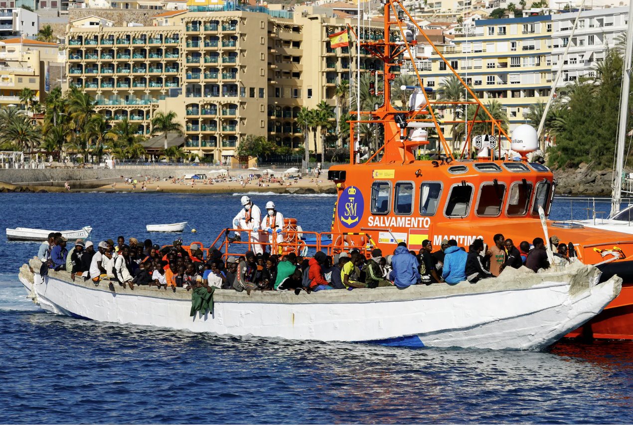 2024年1月2日，在西班牙大加那利岛的阿尔吉内金港，一群移民被一艘西班牙海岸警卫队船只救起后等待从木船上下船。