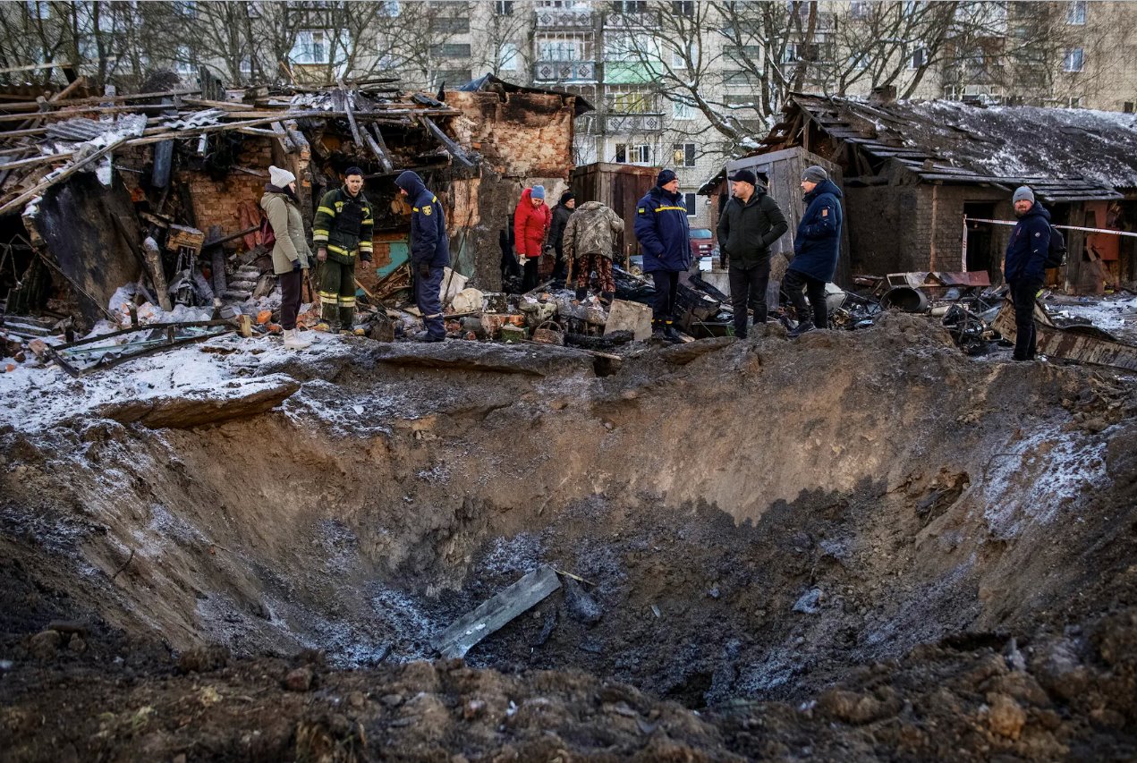 2024年1月13日，乌克兰苏梅地区肖斯特卡镇，当地居民正在查看他们的住宅楼附近的一个弹坑。
