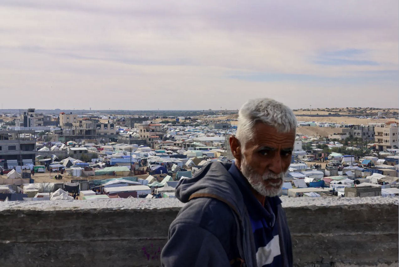 2024年1月21日，加沙地带南部拉法，一名男子在帐篷营地附近观看，因以色列袭击而逃离家园的流离失所的巴勒斯坦人在帐篷营地避难。