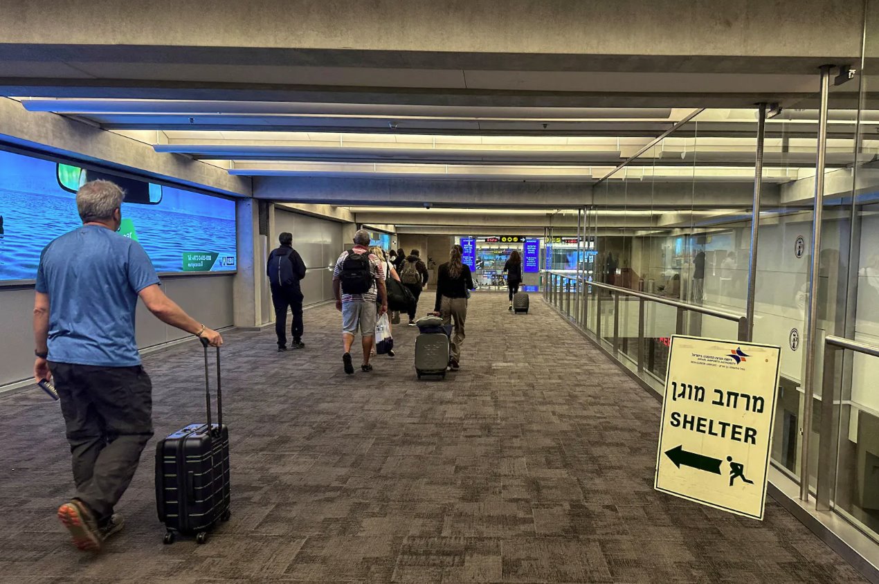 2023年10月11日，以色列特拉维夫附近的本古里安国际机场抵达区，人们在抵达以色列后走过指向庇护所的标志旁边