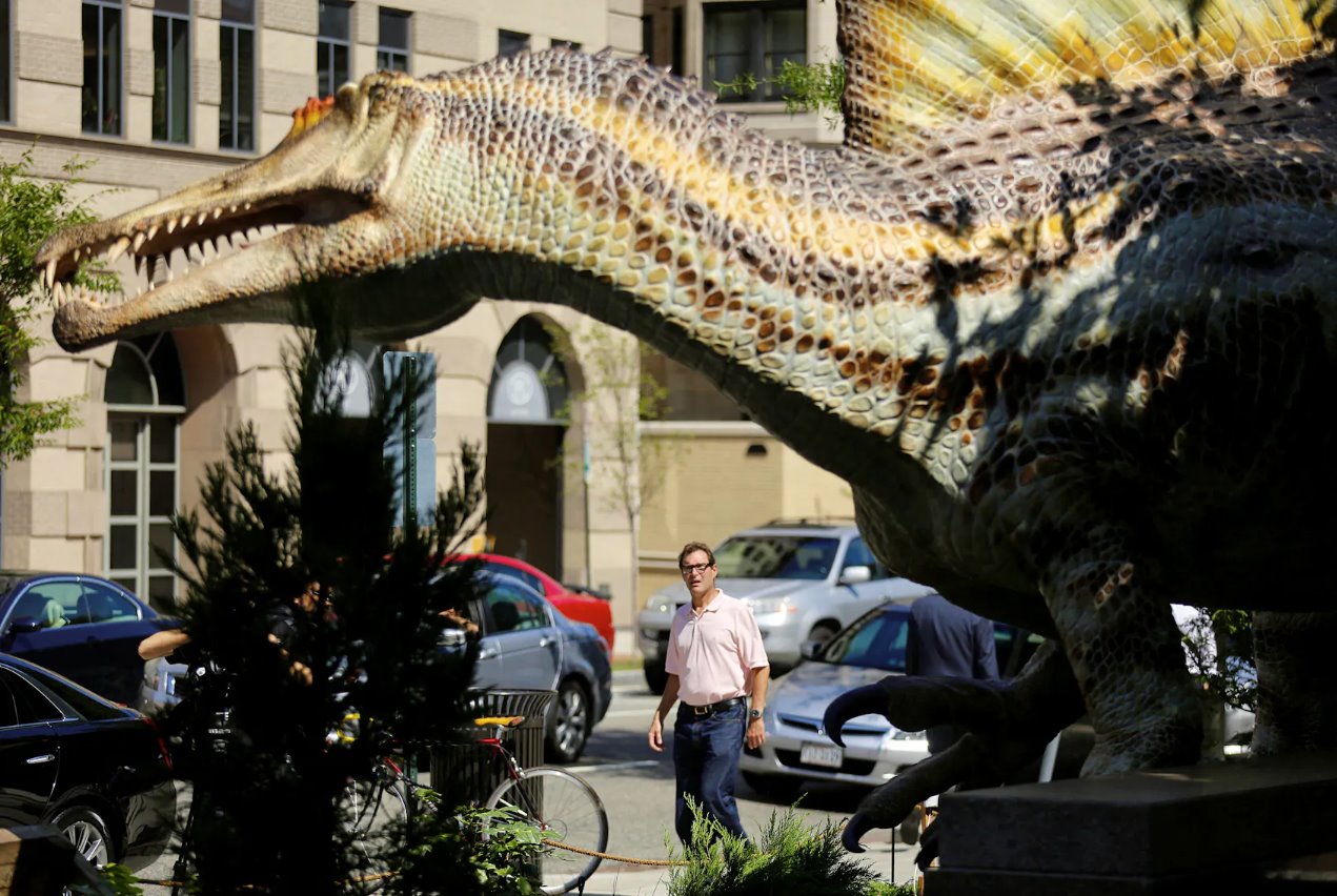 2014年9月11日，华盛顿国家地理学会大楼外，一名行人走过真人大小的棘龙恐龙模型。