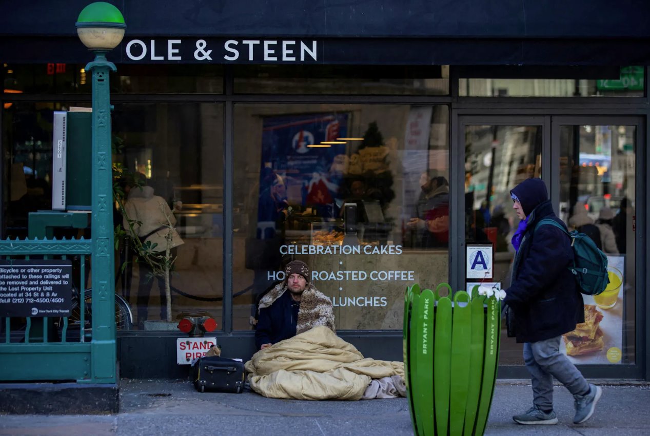 2023年2月4日，美国纽约市，寒冷和大风席卷曼哈顿，一名无家可归者坐在街道上，严寒席卷美国东北部。